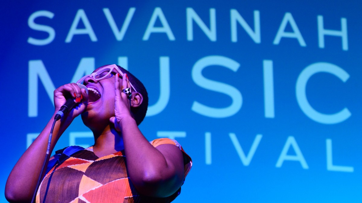 A young woman singing into a microphone on stage.