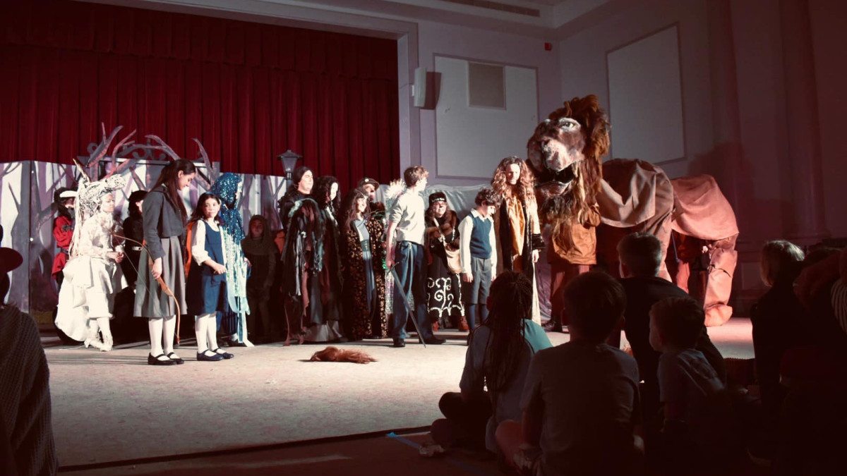 A large cast of people on stage in costume.