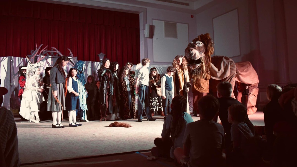 A large cast of people on stage in costume.