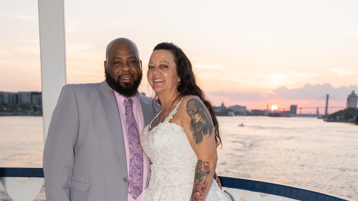 A just married couple standing on a riverboat.