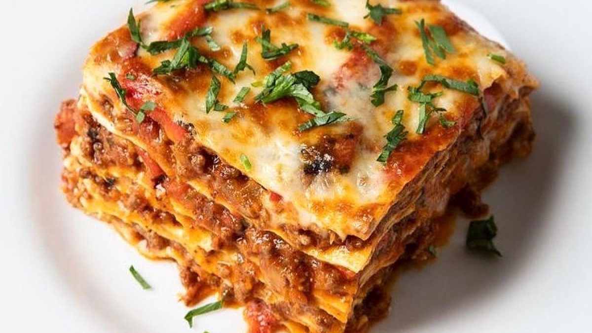 Meaty lasagna served on a white plate.