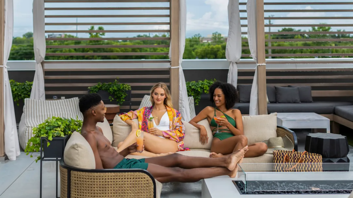 People lounging at a hotel pool deck with drinks.