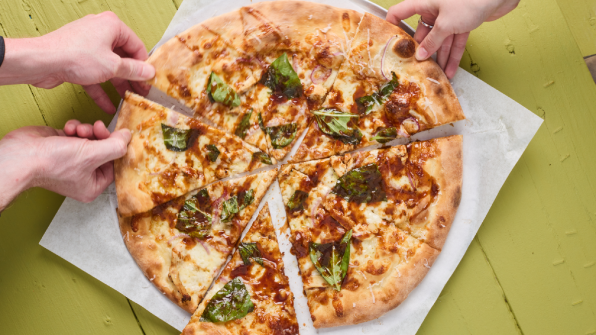 People pulling apart pizza slices.