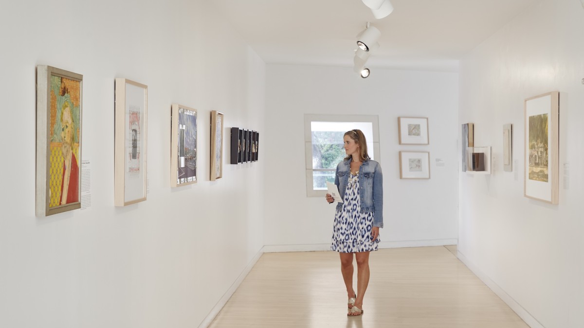 A woman walking and viewing an art gallery.