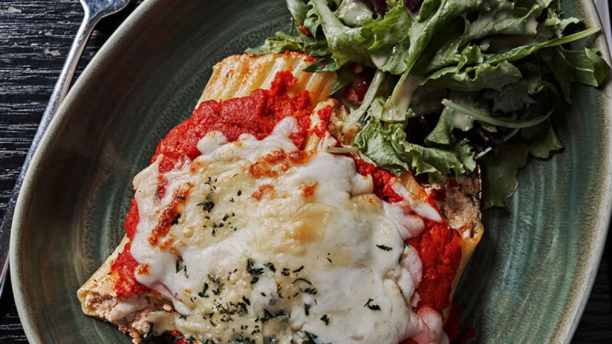 A plate of manicotti with fresh greens.