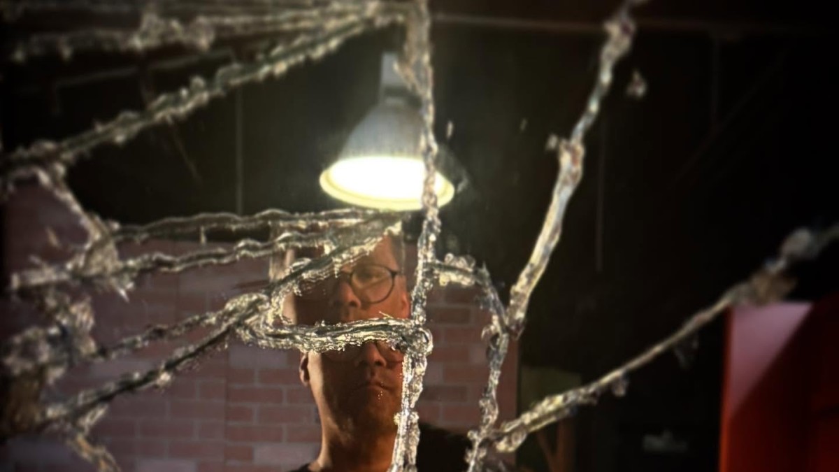 A creepy image of a man standing in front of a broken mirror.