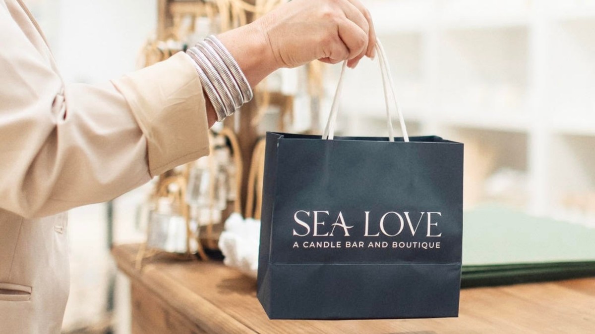 A person’s hand holding a navy blue gift bag in a store