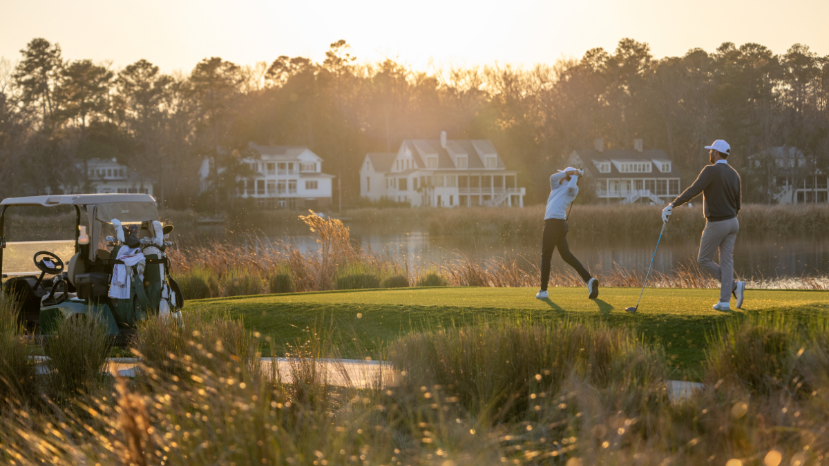 Golfers on the course at sunset.