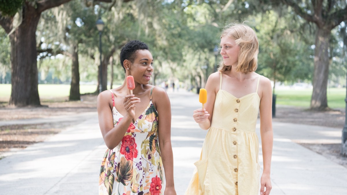 Two friends walking through Forsyth Park eating popsicles in Savannah, GA.