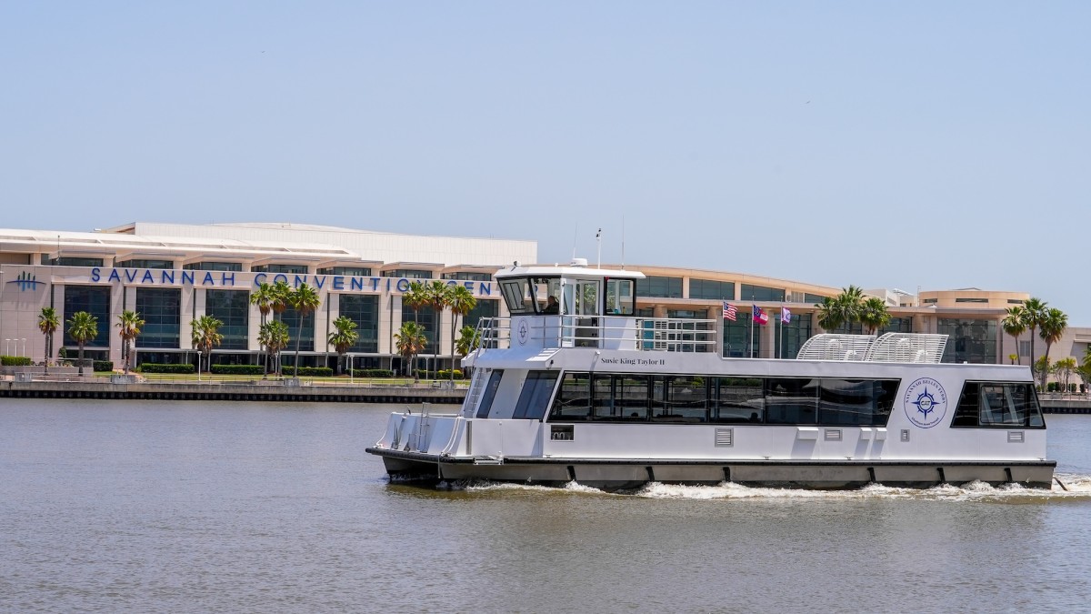 A ferry boat on the Savannah River passing a convention center.