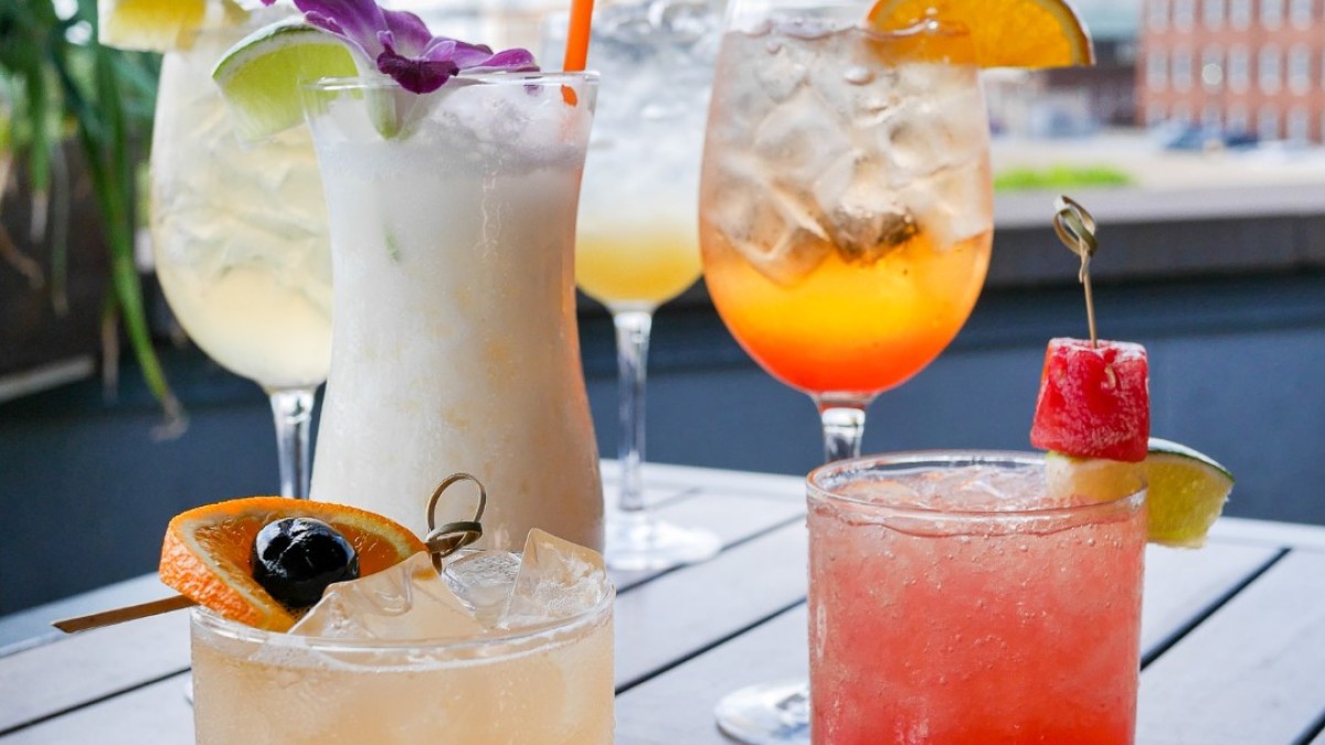 A rooftop bar with several cocktails on a table.