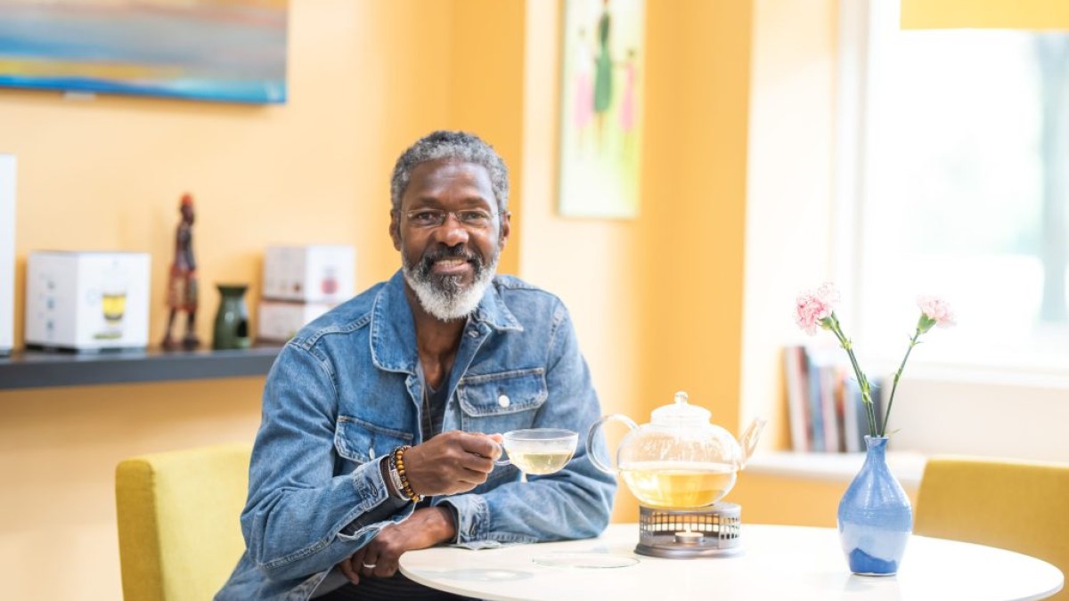 A tea shop owner holding a glass teacup filled with tea.