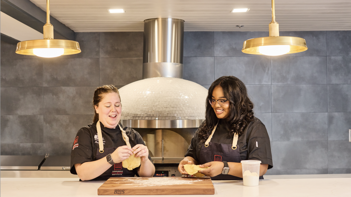 Two culinary students shaping dough.