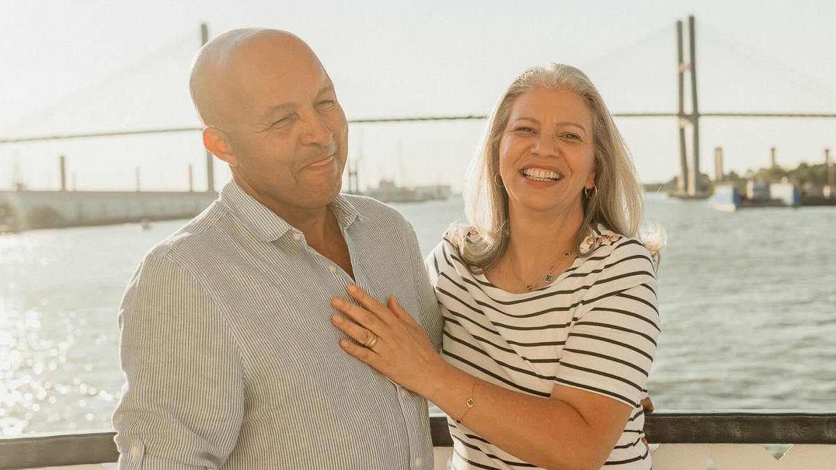 A couple posing for a photo on the outdoor deck of a riverboat.