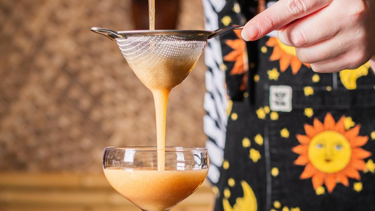 Hands of a bartender crafting a cocktail.
