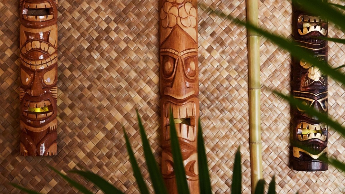 Wooden tiki masks hanging on bamboo walls.