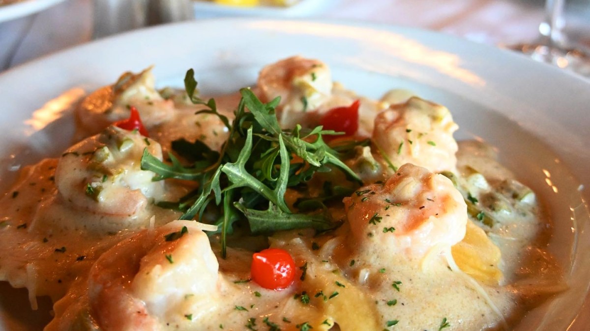 Lobster ravioli topped with shrimp, served on a white plate.