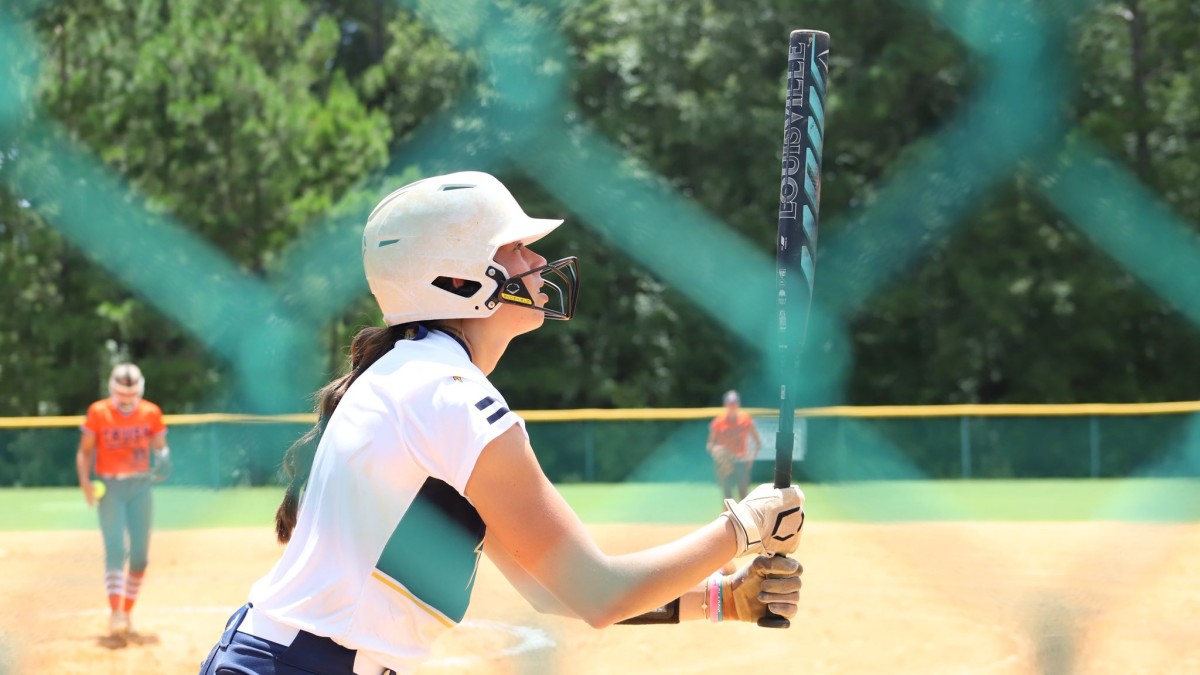 girl holding bat on softball field