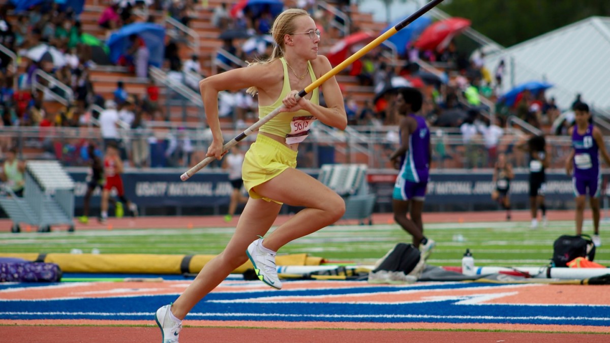 girl with pole vault running on track