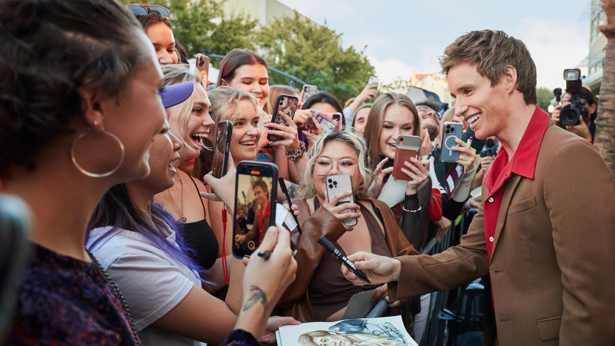 A crowd of people surrounding an actor for photos and autographs.