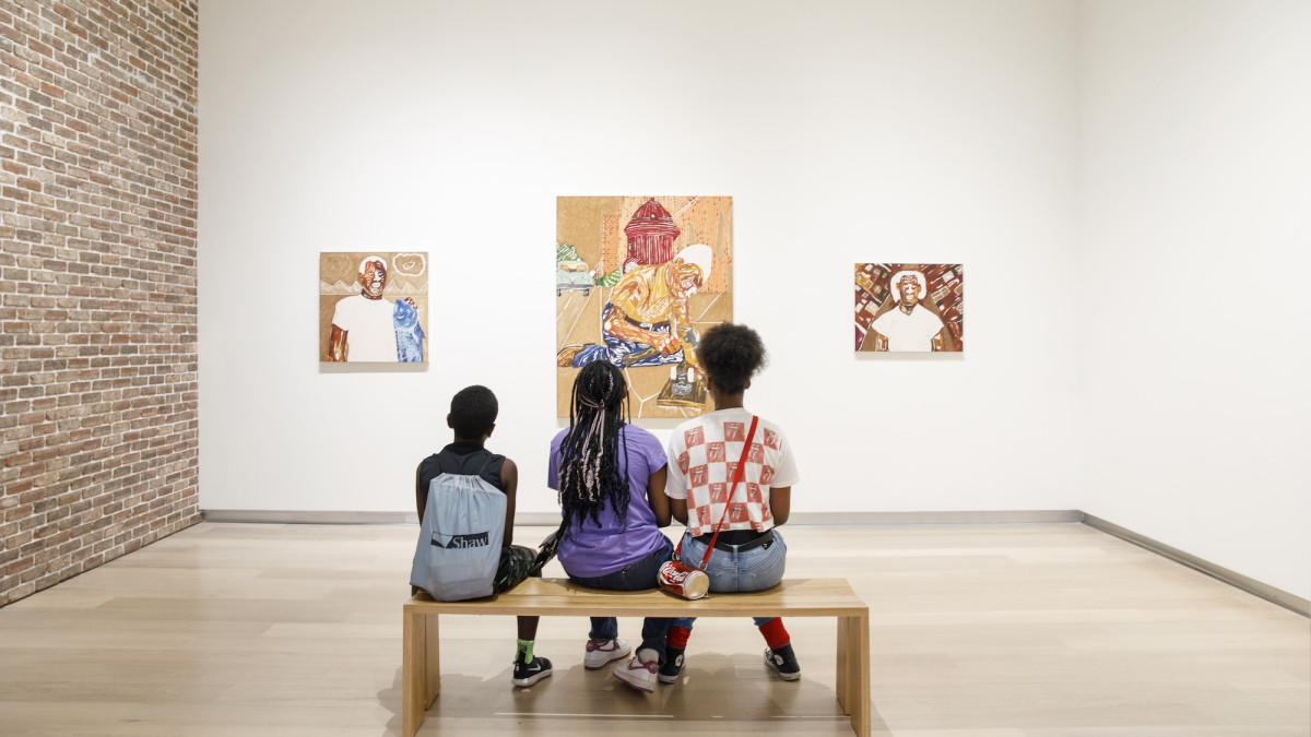 Three young children sitting on a bench admiring art work.