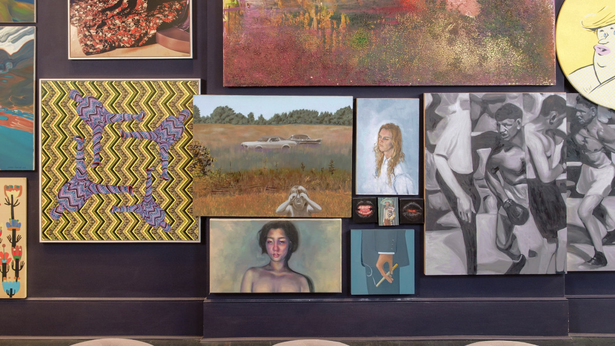 A wall of art paintings for purchase.