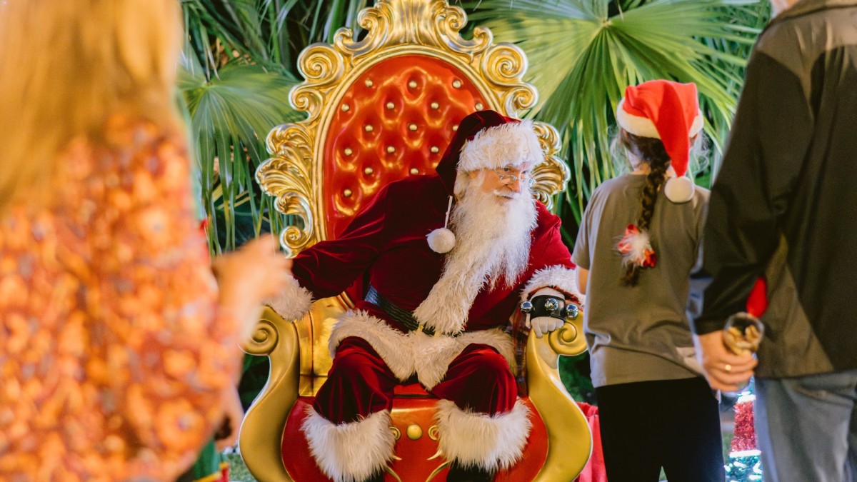 Santa sitting in a large chair talking with children.