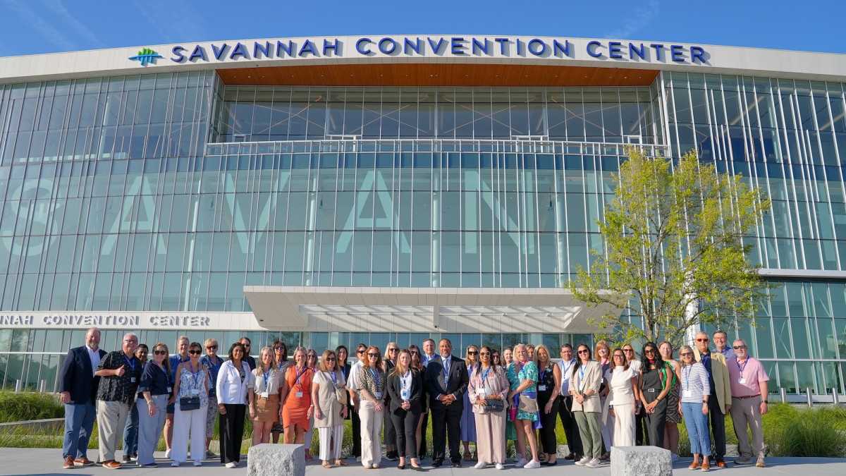 A large group posing for a photo at the front entrance of the Savannah Convention Center.