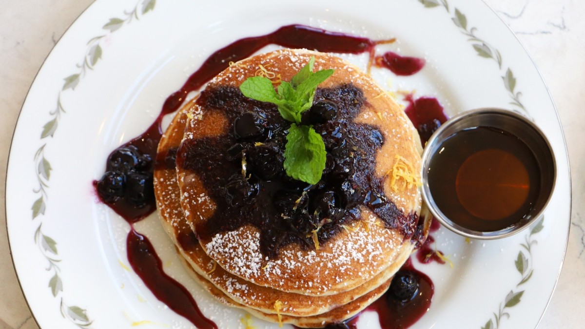Lemon pancakes top with blueberry compote, served in a white dish.