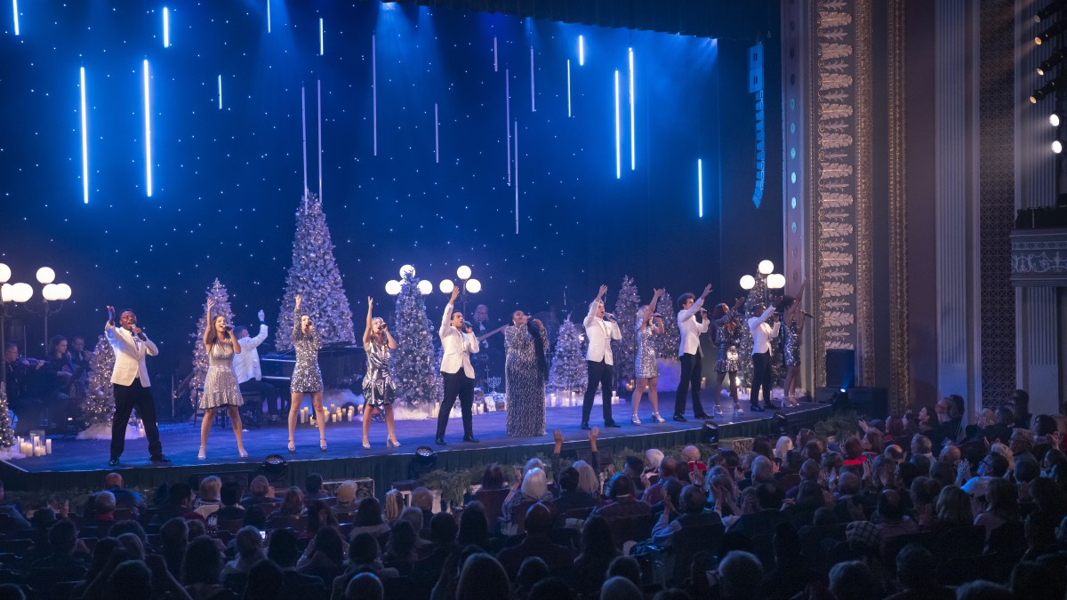 A group of singers on stage performing live for a holiday show.