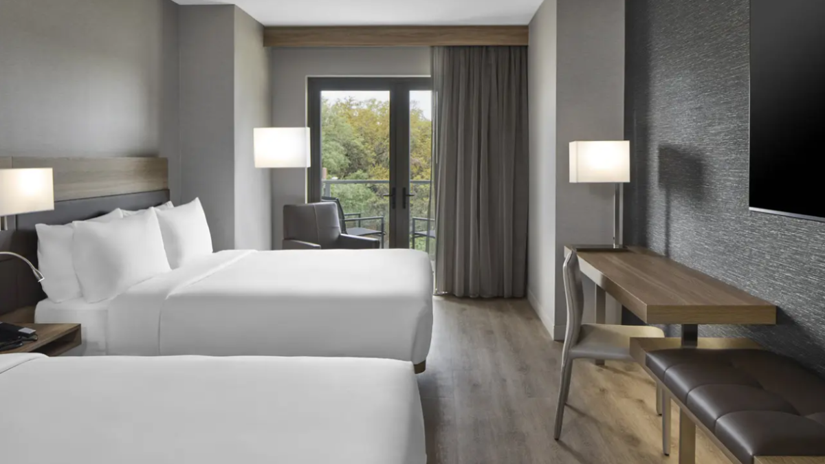 Double queen guest room at AC Hotel Savannah featuring modern design, a work desk and balcony access.