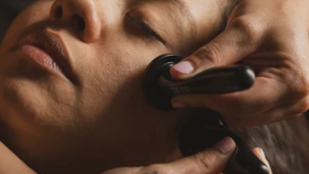A guest relaxes during a lymphatic facial treatment at The Tox Savannah, where smooth black tools are gently used along the jawline and cheeks in a calming spa setting.