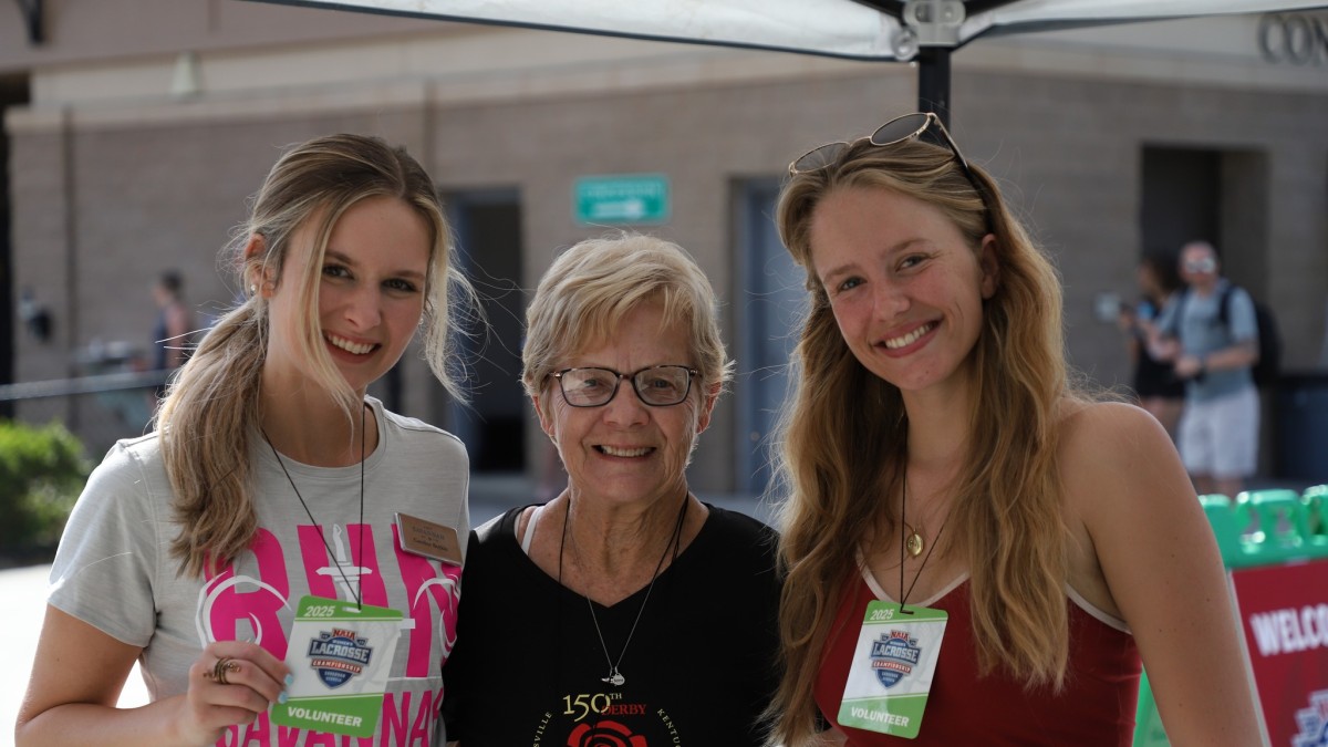 three women smiling with volunteer badges