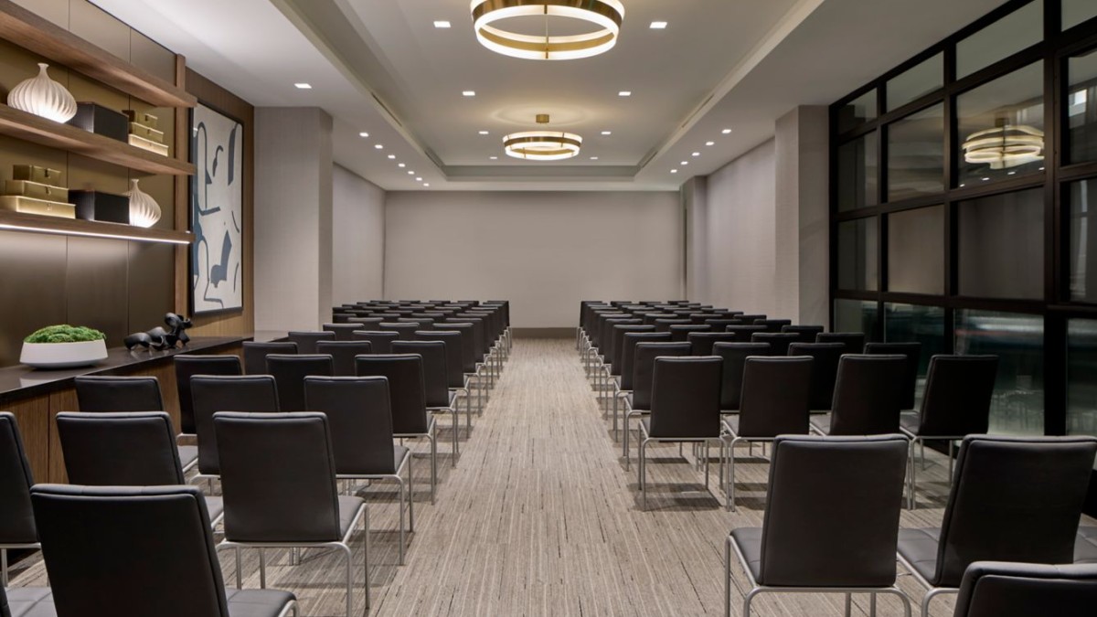 Contemporary event space at AC Hotel Savannah arranged theater-style, featuring clean lines, neutral décor, modern lighting and an intimate, flexible layout ideal for ceremonies or gatherings.