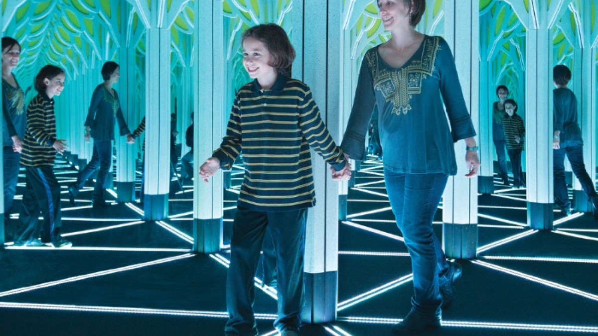 Child and adult explore the illuminated Mirror Maze inside the STEAM Center at Savannah Children's Museum, discovering mathematical patterns through interactive design.