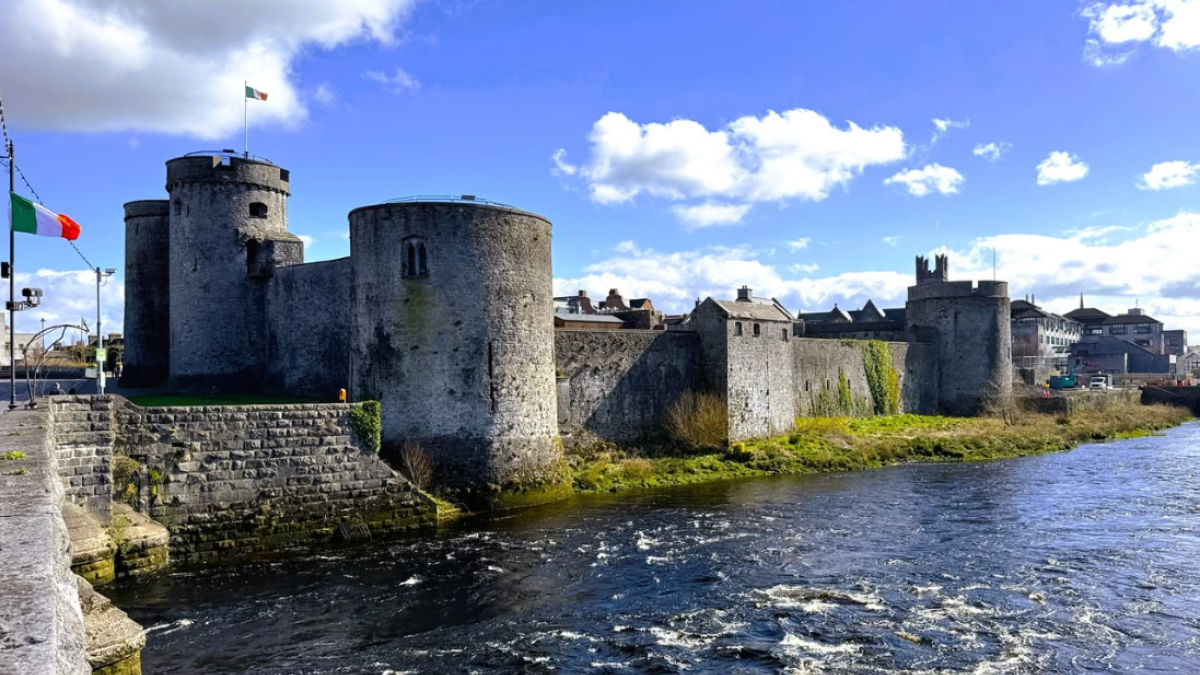 An exterior view of a historic castle surrounded by water in Limerick Ireland.