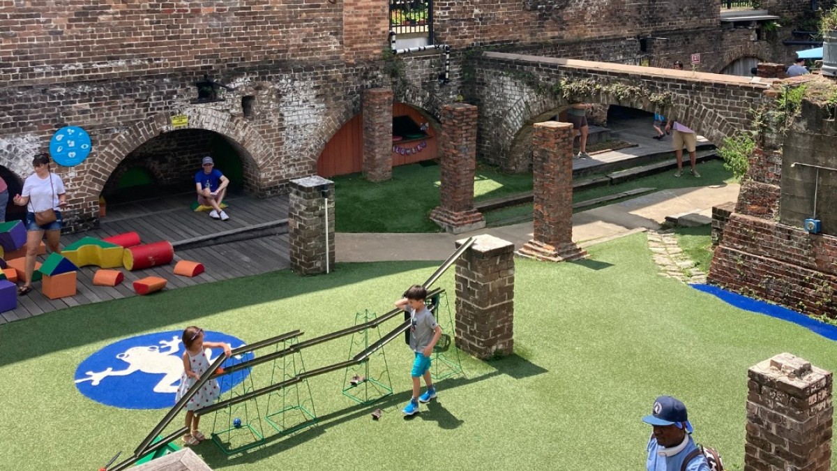 Children and families play among the preserved brick railroad ruins at Savannah Children’s Museum, engaging with interactive outdoor exhibits and open green space.