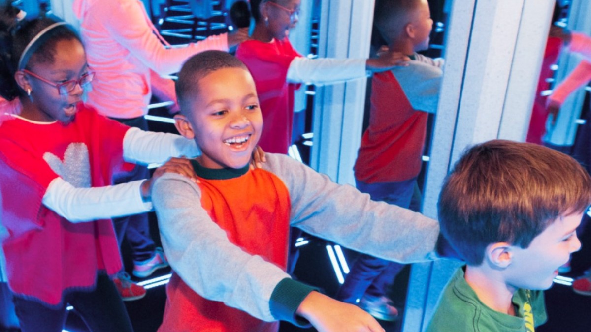 Children explore the illuminated Mirror Maze at the STEAM Center at Savannah Children’s Museum, walking through glowing geometric pathways and mirrored reflections.