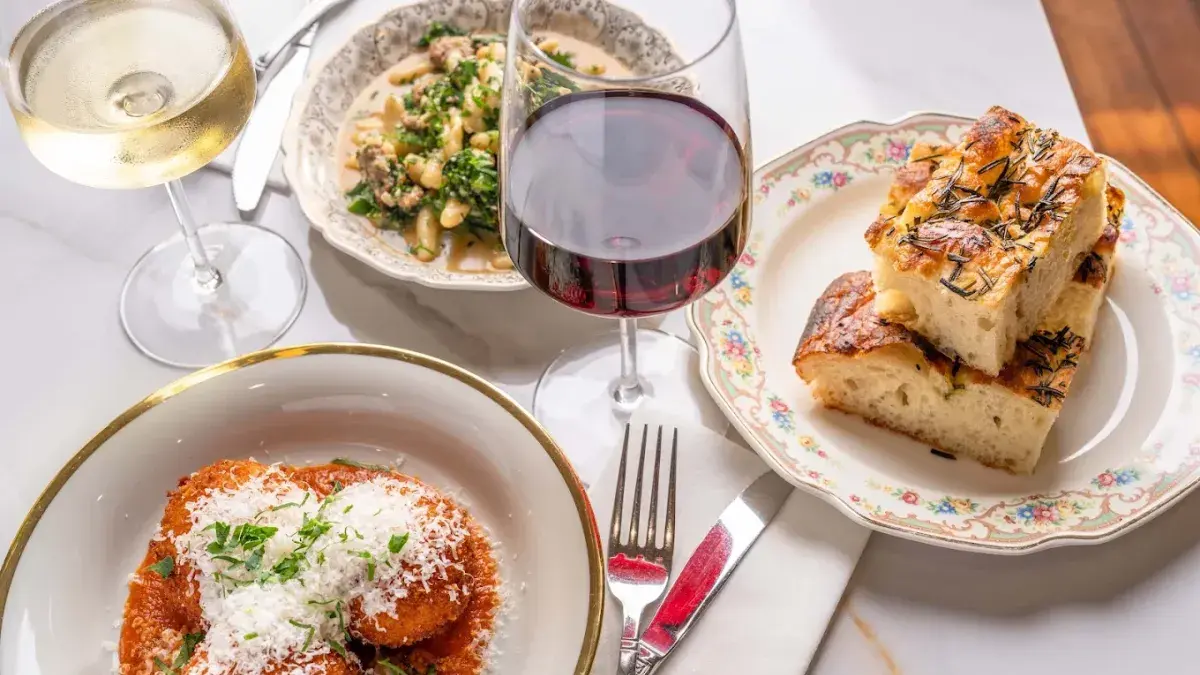 A restaurant table featuring Italian dishes and a glass of red wine.