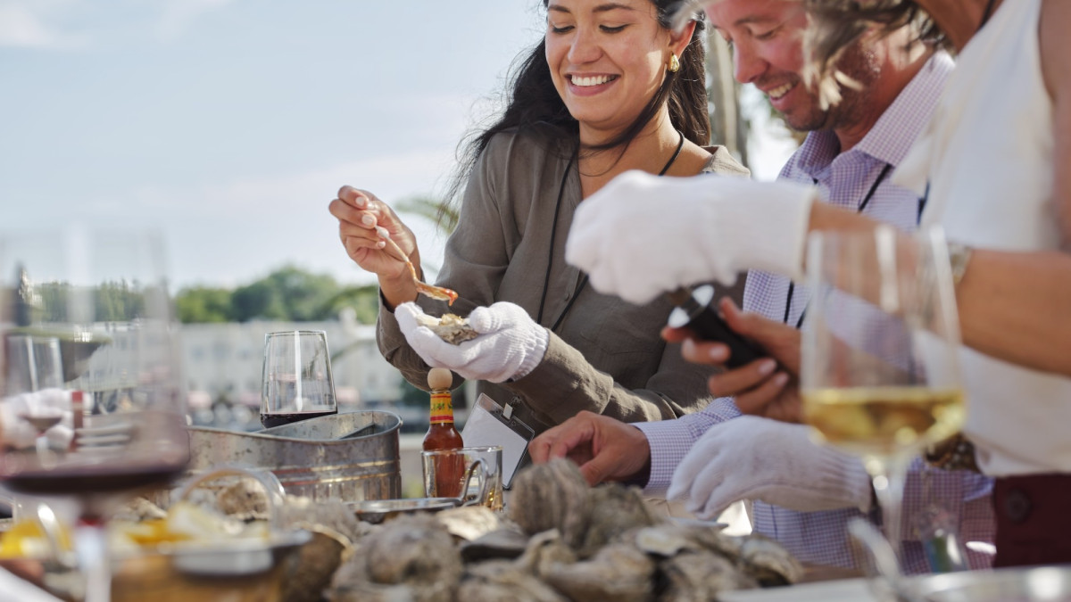 Attendees enjoying oysters and drinks during an outdoor oyster roast at The Westin Savannah Harbor.