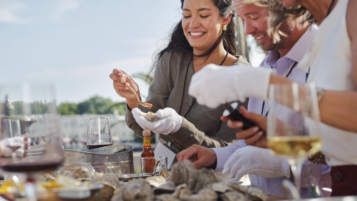 Attendees enjoying oysters and drinks during an outdoor oyster roast at The Westin Savannah Harbor.