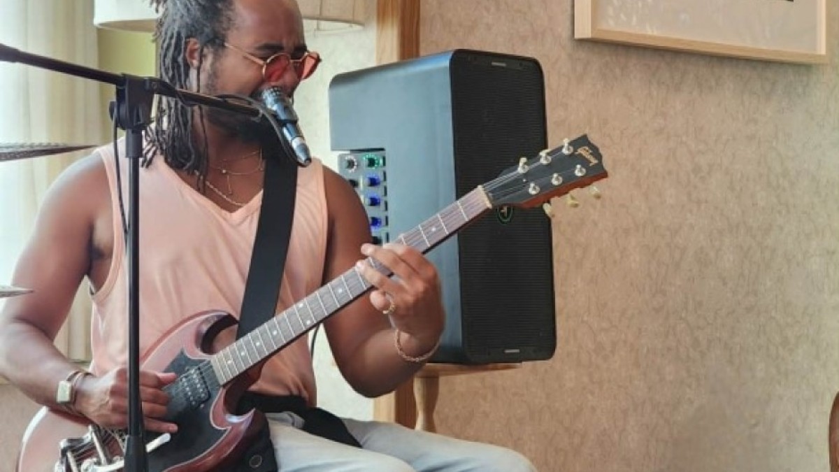 Musician playing electric guitar and singing into a microphone during a live jam session at Little James.