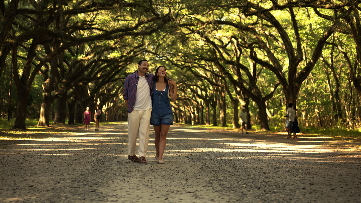 Couple walking together beneath the live oak avenue at Wormsloe Historic Site in Savannah.