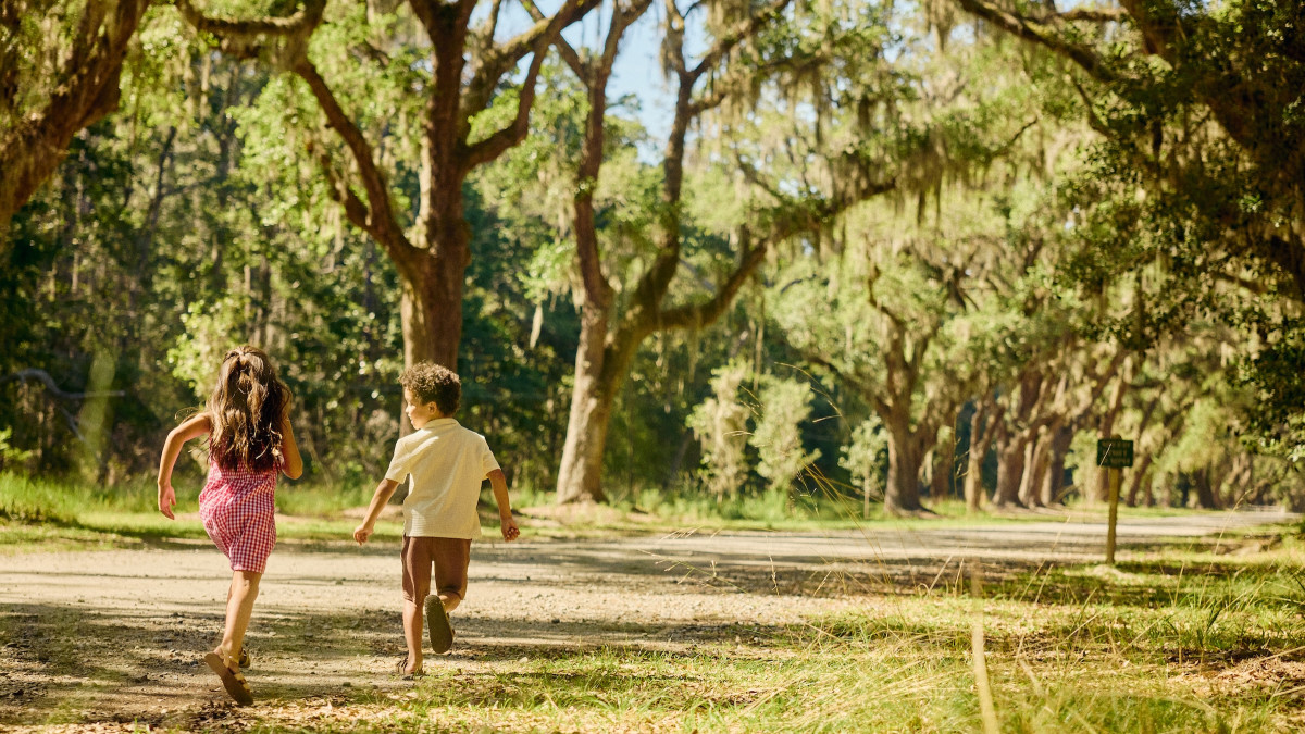 Two children run beneath live oaks draped in Spanish moss at Wormsloe State Historic Site in Savannah.