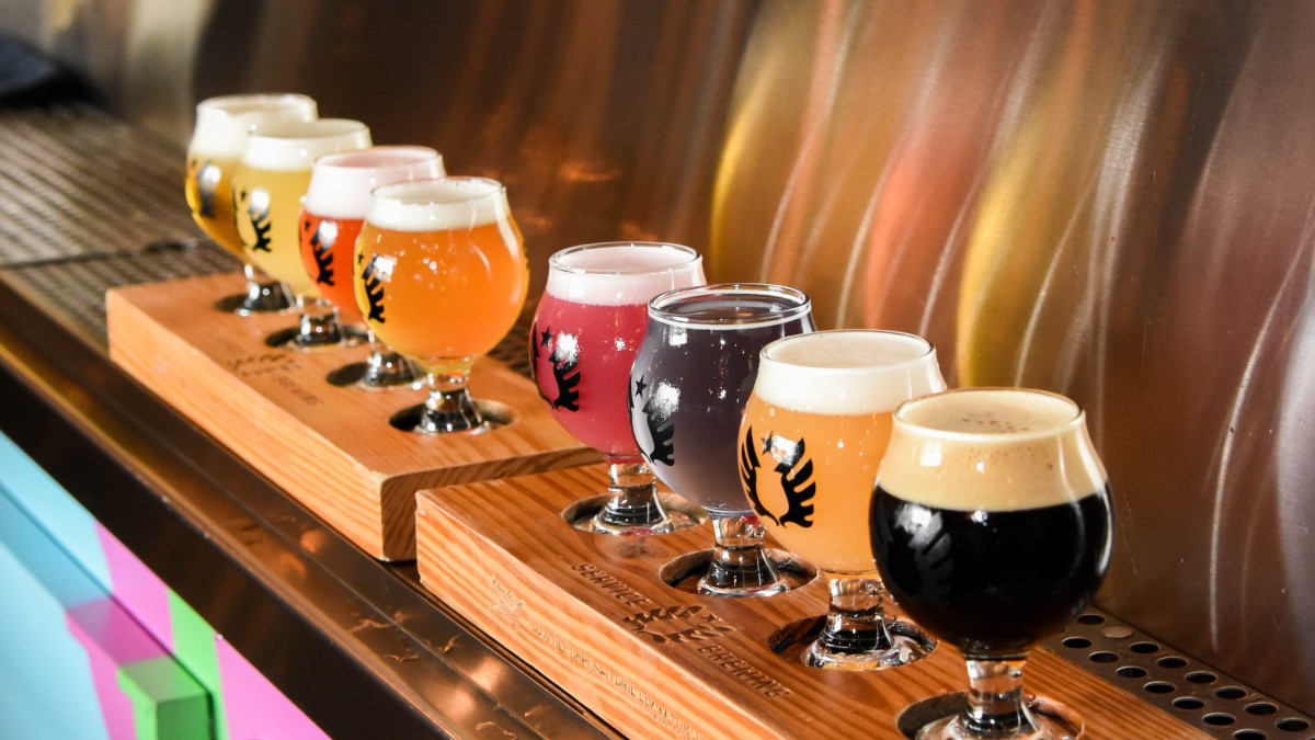 A row of assorted beer flavors below multiple taps.