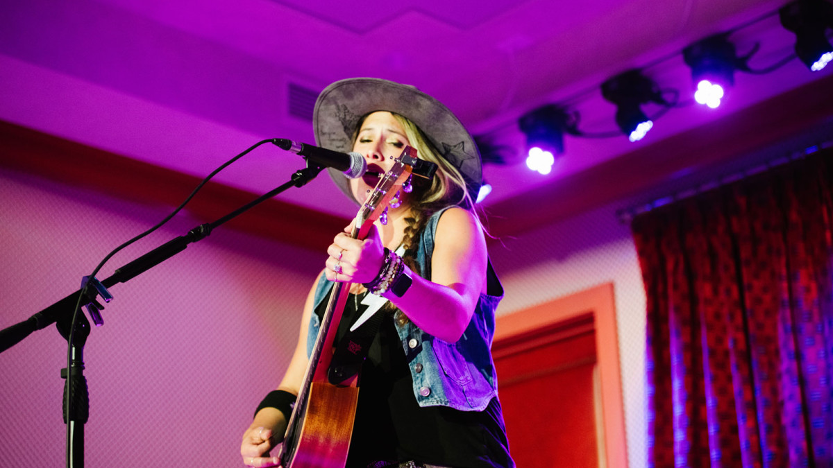 A singer performing onstage with an acoustic guitar.