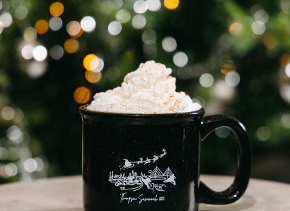 holiday Coquito cocktail with whipped cream in front of a christmas tree