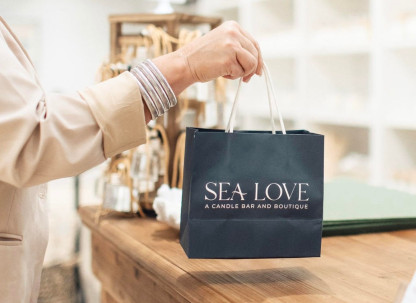 A person’s hand holding a navy blue gift bag in a store