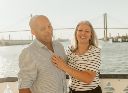 A couple posing for a photo on the outdoor deck of a riverboat.