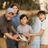 A family of four on the river showing their catch after a day of fishing.